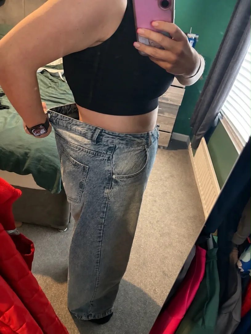 Amy holding out her old jeans, 15kg down