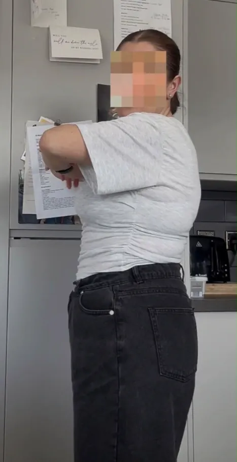 Amy showing the gap in her waistband after losing weight